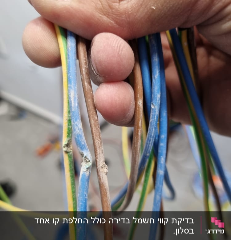 חוטי חשמל צבעוניים מוחזקים ביד עם נזק לבידוד